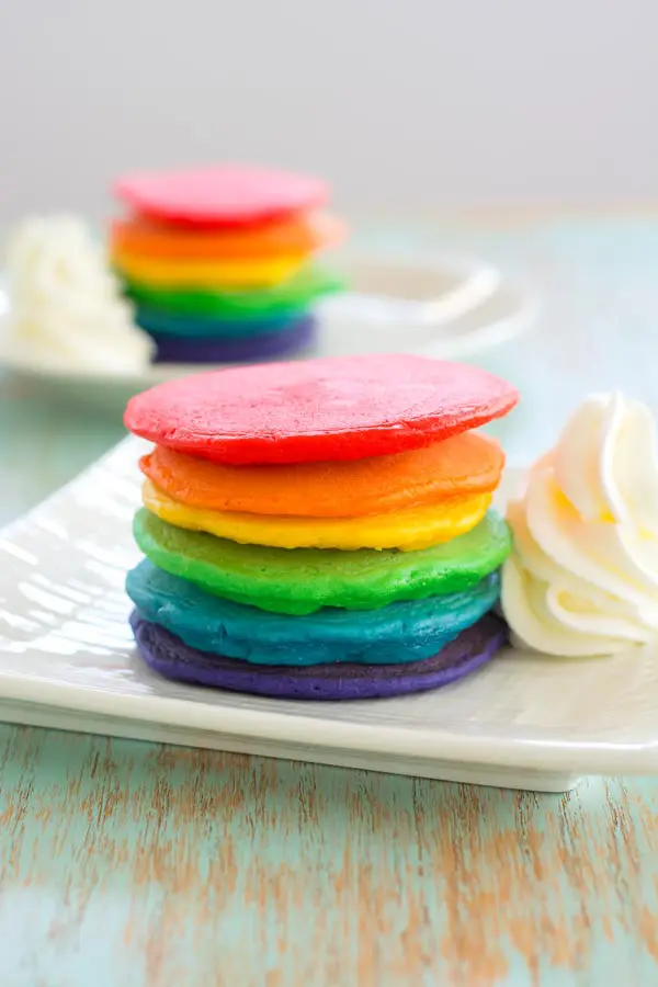 Serve these rainbow pancakes for St. Patrick's Day breakfast! Colored pancakes with fluffy "clouds" of whipped cream are lucky indeed!