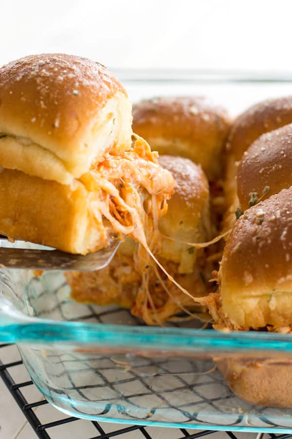 Spatula serving of Slow Cooker Chicken Parmesan Sliders with melted cheese