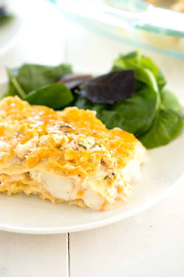 Slice of white chicken lasagna with a salad for an easy dinner recipe!