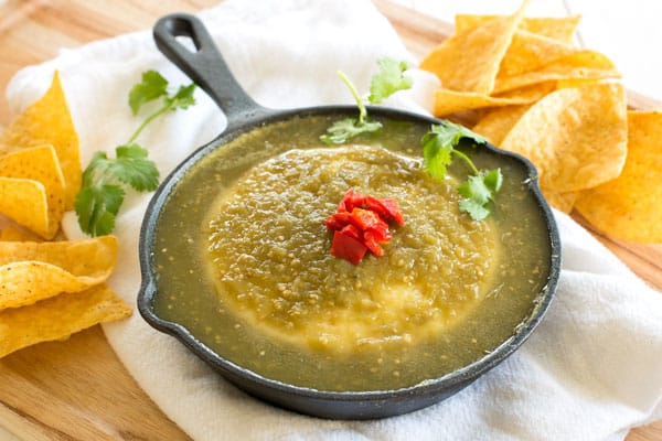 Baked Queso Fresco Dip in green salsa verde. Serve this appetizer in a cast iron skillet with chips!