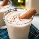 Two glasses of coquito garnished with cinnamon sticks