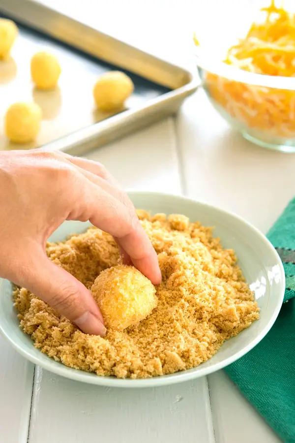 Rolling bolitas de queso (fried cheese balls) in cracker crumbs before frying