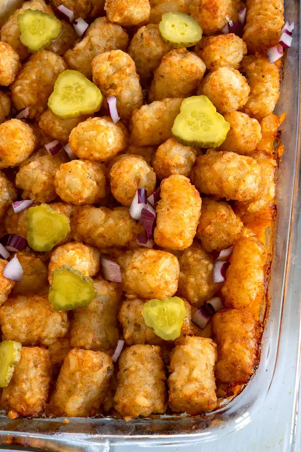 Overhead shot of cheeseburger tater tot casserole topped with pickles and onions