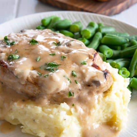 Baked pork chop on mashed potatoes with a side of green beans