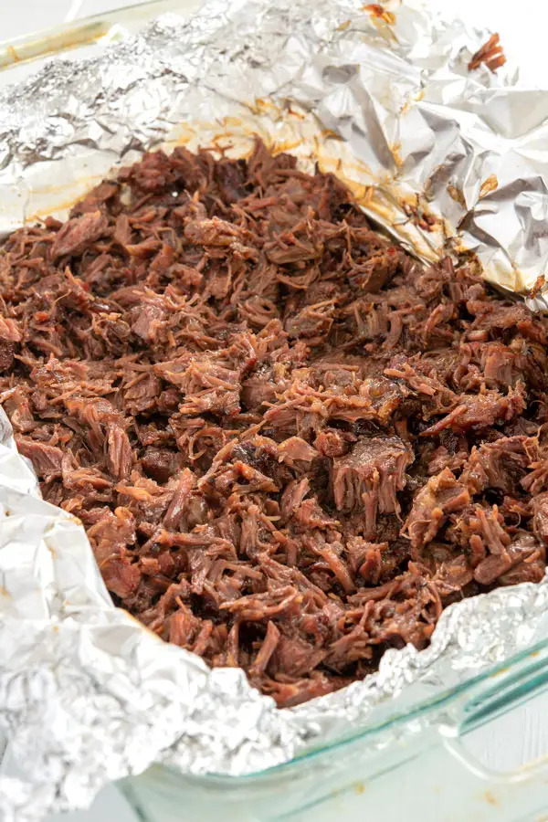 Shredded beef cheek in baking dish for Mexican barbacoa recipe