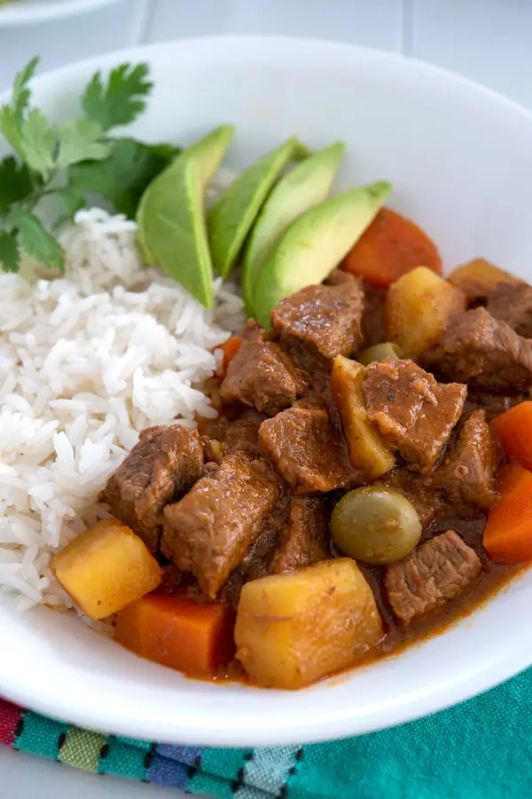 Puerto Rican Carne Guisada served with rice and sliced avocado