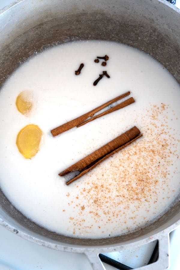 Steeping coconut milk for arroz con dulce with cinnamon, ginger, nutmeg and cloves