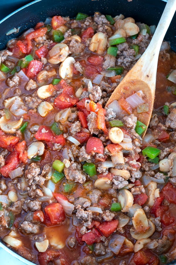 Large skillet with sauce for easy baked spaghetti which includes ground beef, tomatoes, mushrooms, onions and bell pepper