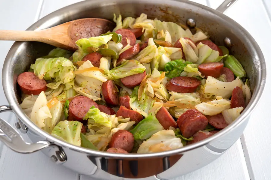 Kielbasa and cabbage in large, silver all-clad skillet