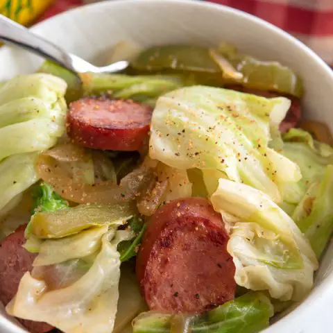 Bowl of kielbasa and cabbage sprinkled with creole spice