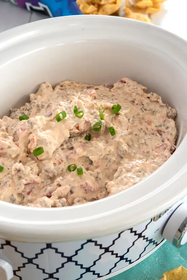 Sausage cream cheese dip in crock pot, garnished with green onions