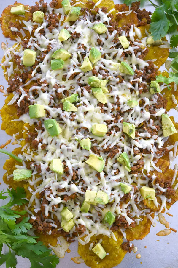 Overhead shot of tostone nachos layered with cheese, picadillo and avocado