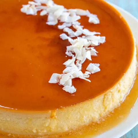 Flan de Coco on a white plate garnished with shredded coconut