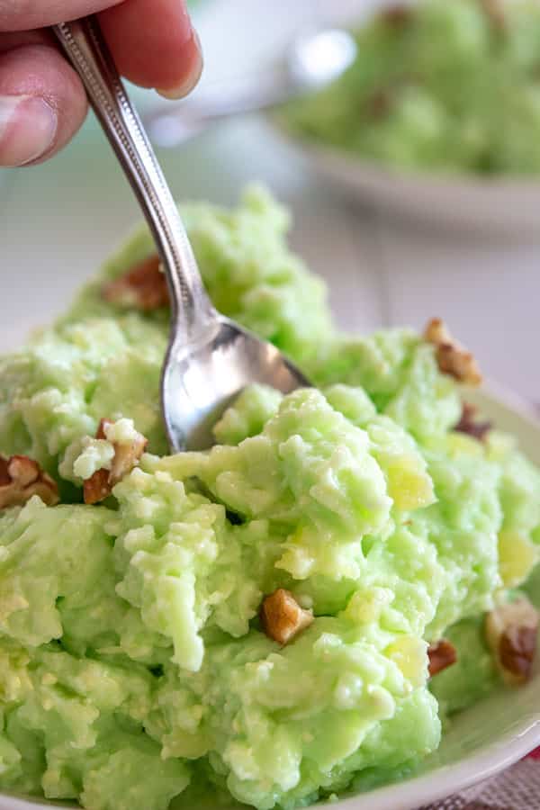 Digging into a serving of lime jello salad with a spoon