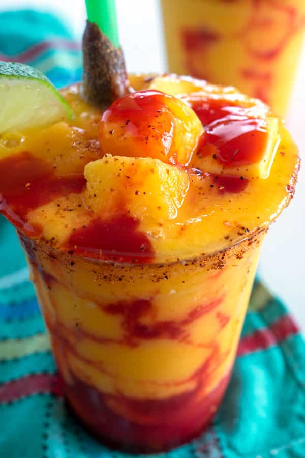 Cup of mangonada garnished with chamoy and tamarind straw