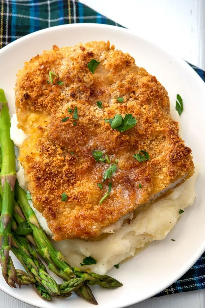 breaded chicken breast over mashed potatoes with asparagus