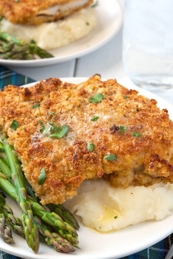 breaded chicken breast over mashed potatoes with asparagus