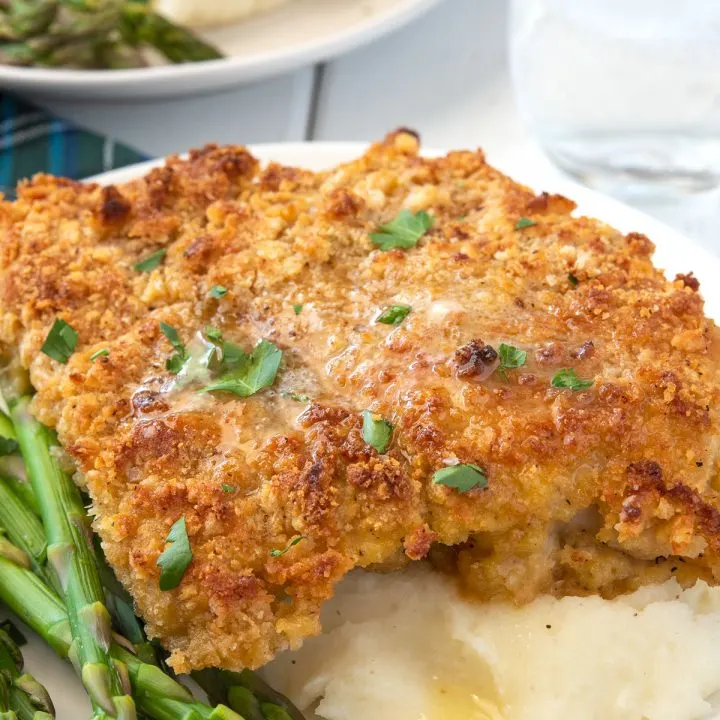 breaded chicken breast over mashed potatoes with asparagus