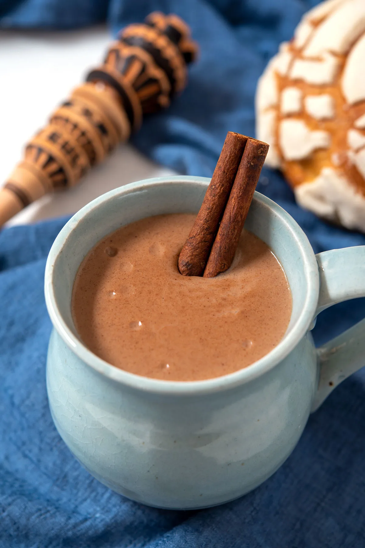 Cup of champurrado garnished with cinnamon stick