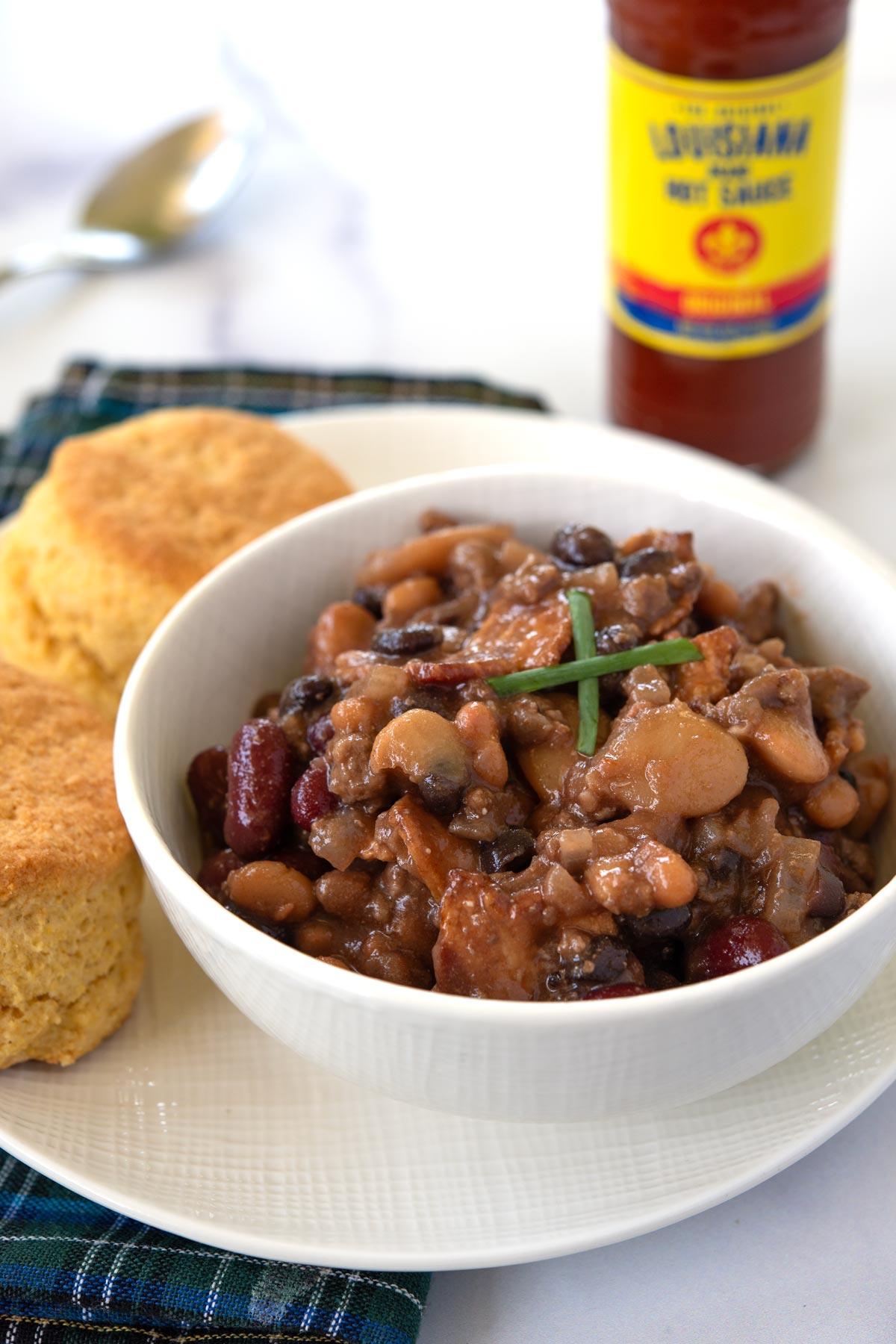 Bowl of Calico Beans with biscuits and hot sauce